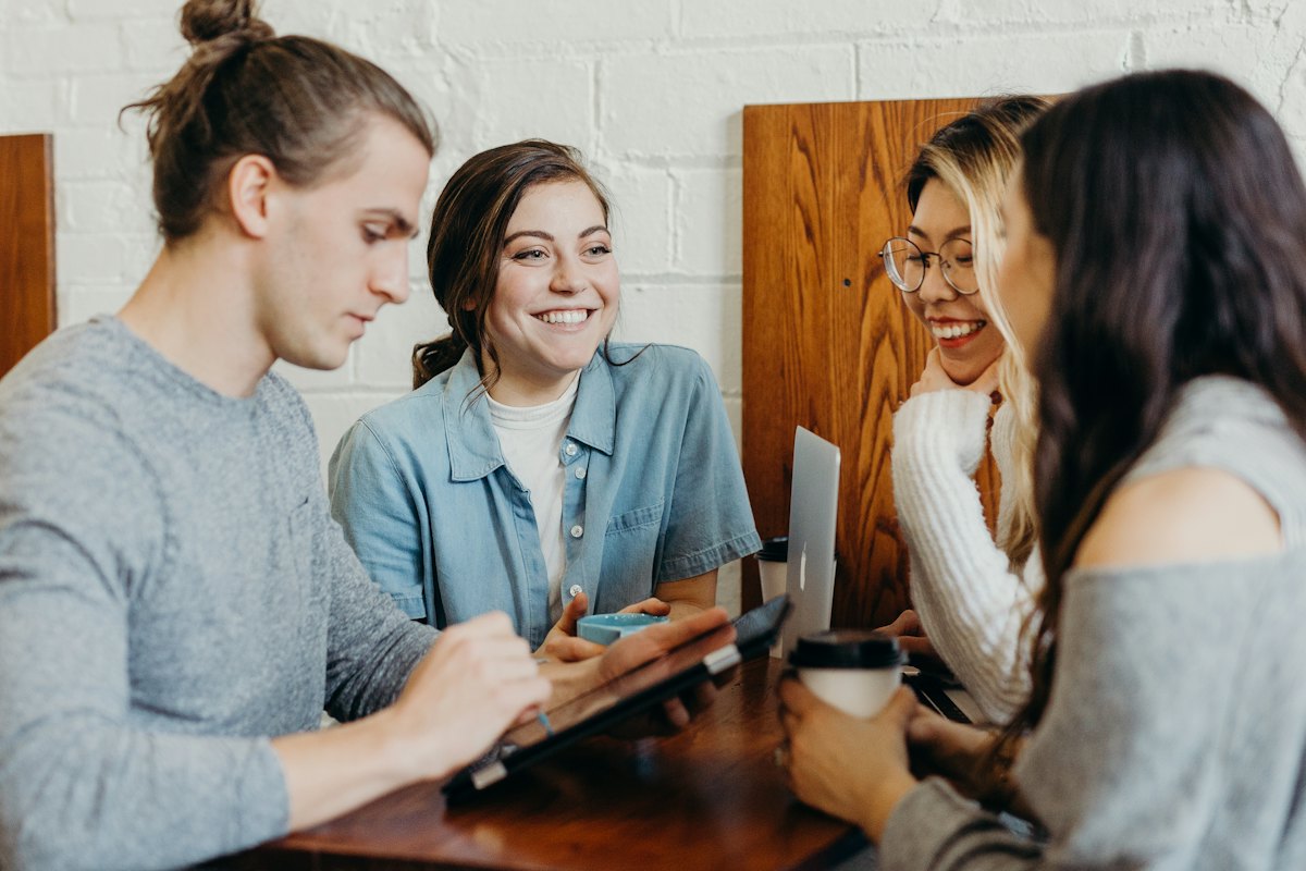 Students talking at a table with a tablet